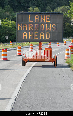 Sicherheitszeichen Kontrolle heißt es "Lane Narrows voraus."  Er warnt Verkehr eine Arbeit Zone Gefahren. Orange-weiße reflektierende Leitpfosten Beiträge Anleitung Auto fließen. Stockfoto