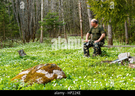 Frühling ist der Moment für Blume. Schneeglöckchen-Anemone. Mann mit einer Axt sitzen auf einer Bank in der Form der Jagd. Stockfoto