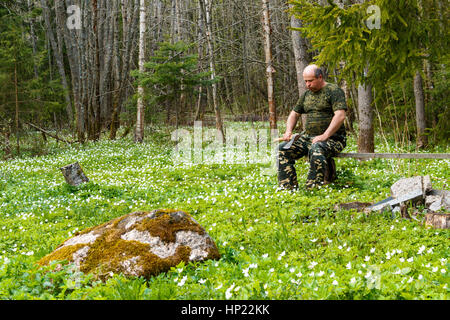Frühling ist der Moment für Blume. Schneeglöckchen-Anemone. Mann mit einer Axt sitzen auf einer Bank in der Form der Jagd. Stockfoto