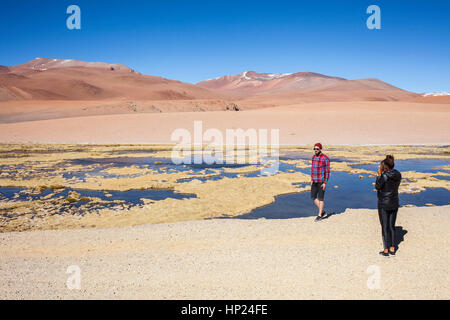 Touristen, Mann und Frau, halten in der Straße nach Argentinien, Altiplano, Puna, in der Nähe von Salar de Aguas Calientes und Salar de Tara, Atacama Wüste. Chile Stockfoto