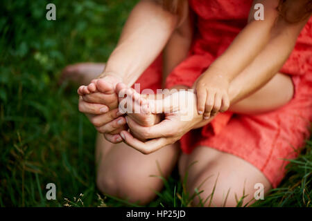Mutter mit einem Kind, finden Sie unter den Händen von Müttern und Babys Füße. Das Gefühl von Pflege und Mutterschaft. Stockfoto
