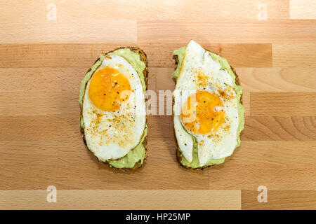 Gesunden Avocado-Toast und Spiegelei auf Vollkornbrot auf hölzernen Hintergrund zum Frühstück Stockfoto