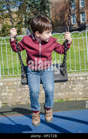 Ein kleiner Junge spielt auf einer Schaukel auf einem Kinderspielplatz. Stockfoto