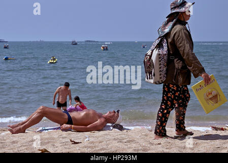 Männliche Touristen Sonnenbaden am Strand von Pattaya Thailand mit Getränke-Hersteller vorbei. Stockfoto