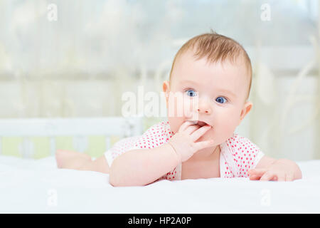 Lustige Baby Kleinkind Kind mit blauen Augen auf dem Bett liegend Stockfoto