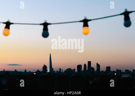 Blick auf London Skyline Silhouette aus einem Freiluftkino-Party im Bussey Gebäude auf dem Dach, Peckham, während des Sonnenuntergangs. Stockfoto