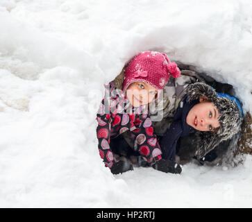 Jungen und Mädchen versteckt in einer Schneehöhle machten Sie Stockfoto