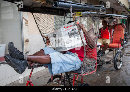 Tri Taxi, Dreirad, Mann, der Granma Zeitung liest, wartet auf Kunden, Street Scene, San Rafael Straße an der Galiano avenida, Centro Habana, Haban Stockfoto