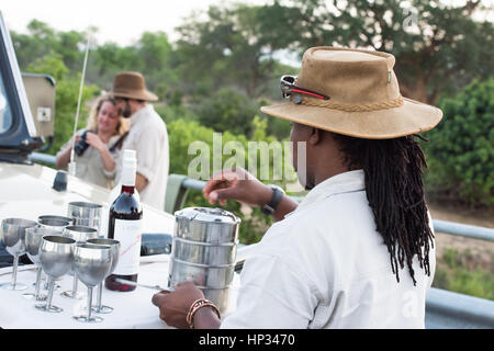 Krüger-Nationalpark, Südafrika - 27. November 2016: Ein Reiseleiter Sundowner Getränke und Snacks an der Vorderseite des seine 4 x 4-Fahrzeug mit einem c bereitet Stockfoto