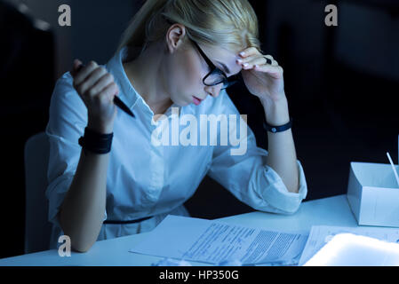 Aufmerksame junge Frau, die im Büro arbeiten Stockfoto