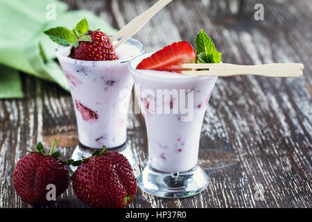 Gefrorene Frucht-Smoothies mit frischen Erdbeeren serviert in gekühlte Gläser hoch oben, Sommer süß behandeln Stockfoto