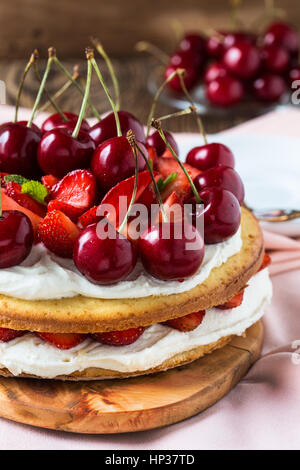 Hausgemachte Sahne Torte, frisch, bunt, und leckeres Dessert mit saftigen Erdbeeren, süßen Kirschen und Schlagsahne Stockfoto