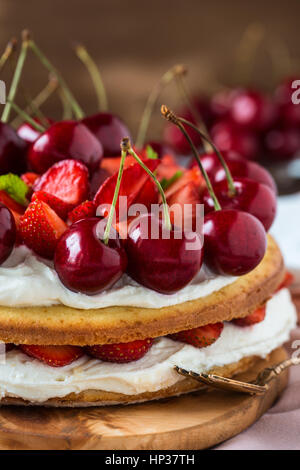 Hausgemachte Sahne Torte, frisch, bunt, und leckeres Dessert mit saftigen Erdbeeren, süßen Kirschen und Schlagsahne Stockfoto