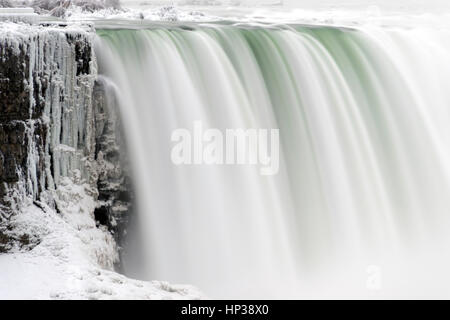 Nahaufnahme von starken Wasserfall fließt über Eis bedeckt, Klippe, glatte Wasser und tief Aqua Farben Stockfoto