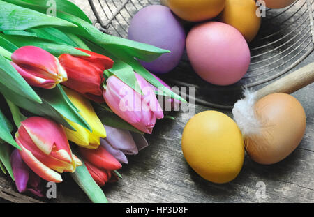 bemalten Eiern mit Haufen von Tulpen auf hölzernen Hintergrund Stockfoto