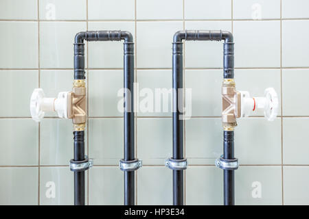 Wasserleitungen mit Ventilen an der Wand Stockfoto