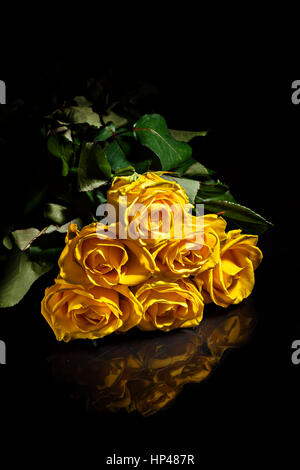 ein Bouquet von gelben Rosen mit Tropfen auf einem dunklen Hintergrund. Stockfoto