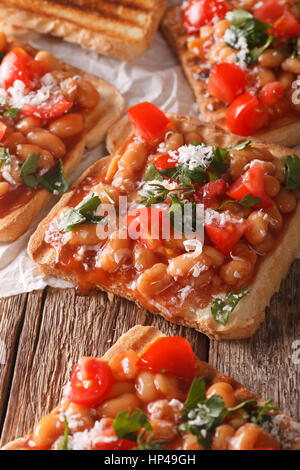 Toast mit Bohnen in einer Tomaten-Sauce, Käse und Kräutern Nahaufnahme auf dem Tisch. vertikale Stockfoto