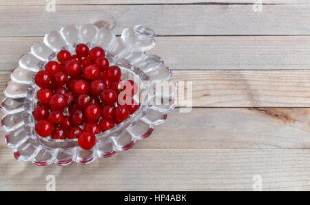 Bio-Garten Beeren auf alten Holztisch von oben. Rote Johannisbeere. Kristallvase in der Form von Herzen Stockfoto