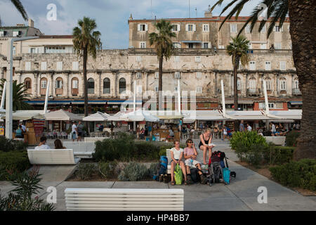 Eine Reisende Familie nimmt eine Auszeit in der Riva Uferpromenade vor der Südfassade des Diokletian Palastes. Split, Kroatien Stockfoto