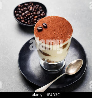 Tiramisu, traditionelle italienische Dessert im Glas Stein grau unterlegt. Textfreiraum Stockfoto