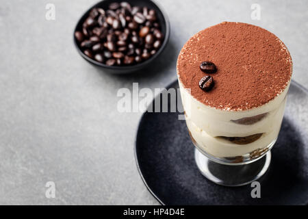 Tiramisu, traditionelle italienische Dessert im Glas Stein grau unterlegt. Textfreiraum Stockfoto