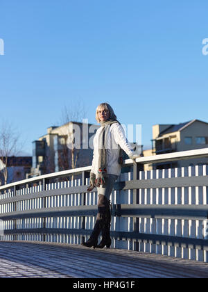 Reife Frau lehnt sich an das Geländer der Brücke, sonnigen Wintertag Stockfoto