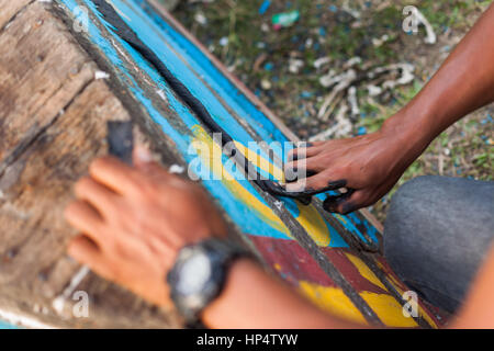 Nepali Mann repariert ein Ruderboot die traditionelle Art, mit Baumwoll-Seil und Teer Stockfoto