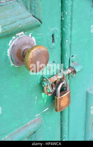 Alte, sichere, mit einem Vorhängeschloss gesicherte grüne Tür Stockfoto