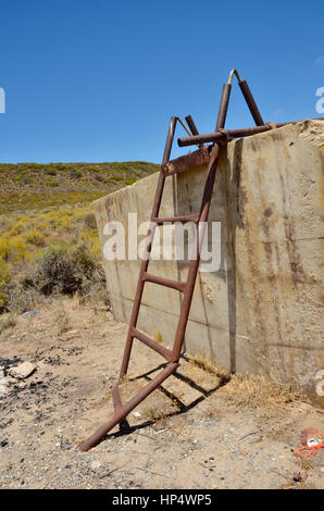 Gebrochen, rostigen Metall-Leiter an einer Betonwand Stockfoto