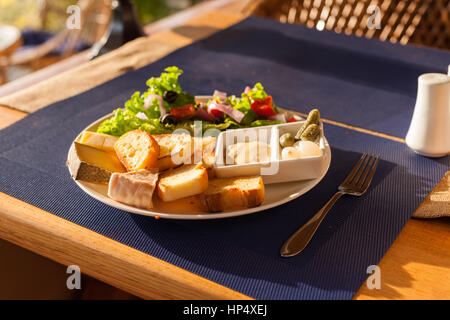 Eine französische Käse-Platte mit Tomme, Belkot und Saint-Marcellin Käse, Salat, Dijon-Senf, Essiggurken und Schalotten Stockfoto