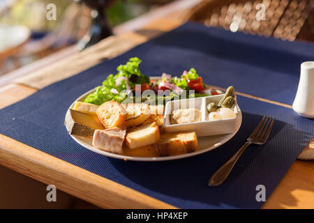 Eine französische Käse-Platte mit Tomme, Belkot und Saint-Marcellin Käse, Salat, Dijon-Senf, Essiggurken und Schalotten Stockfoto