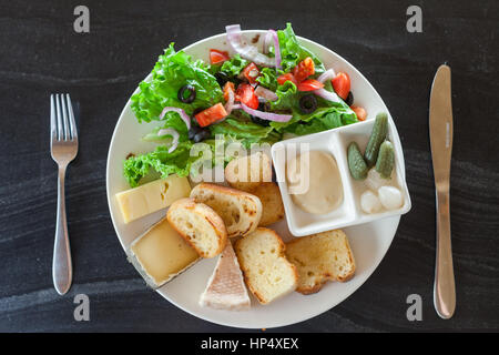 Eine französische Käse-Platte mit Tomme, Belkot und Saint-Marcellin Käse, Salat, Dijon-Senf, Essiggurken und Schalotten Stockfoto