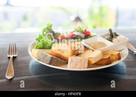 Eine französische Käse-Platte mit Tomme, Belkot und Saint-Marcellin Käse, Salat, Dijon-Senf, Essiggurken und Schalotten Stockfoto