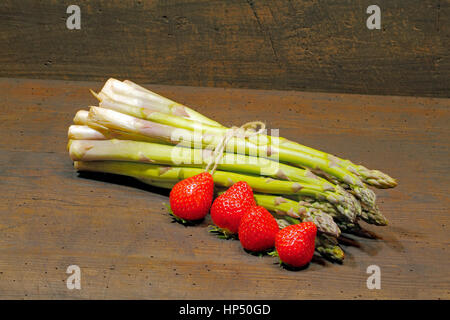 Erntefrische Spargel und Erdbeeren auf einem urigen, alten Holzbrett Stockfoto