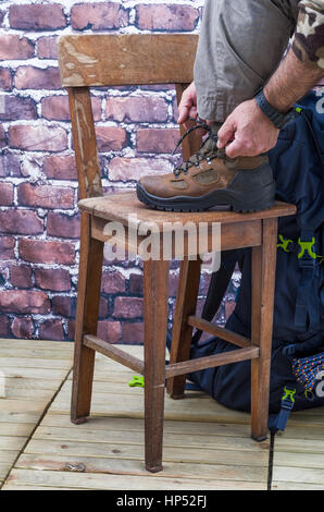 Schließen, der eine Person, die Stiefel trägt für Trekking- und Mountainbike, mit nah Werkzeuge und Zubehör wie einen Kompass, Rucksack, Trinkflasche und Ax Roc Stockfoto