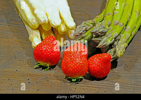 Erntefrische Spargel und Erdbeeren auf einem urigen, alten Holzbrett Stockfoto