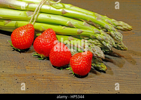 Erntefrische Spargel und Erdbeeren auf einem urigen, alten Holzbrett Stockfoto
