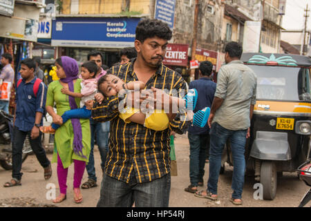 Mumbai, Indien - 11. Dezember 2016 - Mann trägt sein Kind bewegt sich langsam in der sehr belebten Straßen und Verkehr in Mumbai mit Tuk-Tuk und taxis Stockfoto