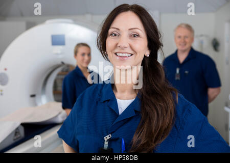 Lächelnd weibliche Radiologen mit Kollegen stehen durch MRI-Machi Stockfoto