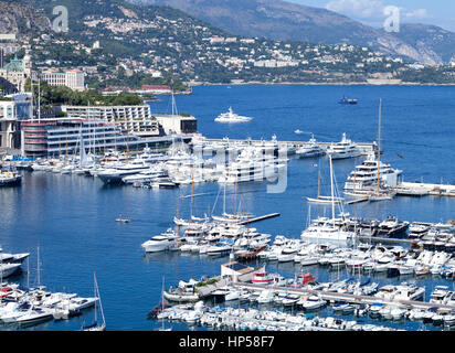 Beschäftigt Monaco Hafen mit Super, Mega-Yachten, Schiffe, Segelboote mit Monte-Carlo im Hintergrund Stockfoto