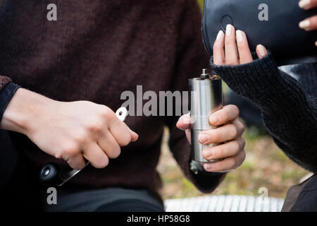 Frau Gießen Kaffeebohnen in Grinder Gehalten von Man Stockfoto