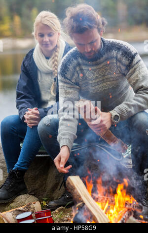 Paar durch Lagerfeuer sitzen auf Lakeshore Stockfoto