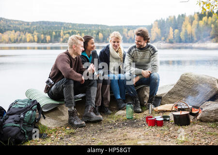 Freunde sprechen am Seeufer beim Camping Stockfoto