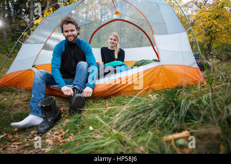 Mann mit Boot, während Frau Entspannen im Zelt Stockfoto