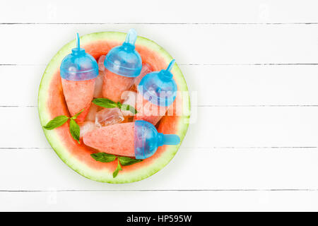 Eis am Stiel der Wassermelone mit Minze auf hölzernen Hintergrund. Flach zu legen Stockfoto