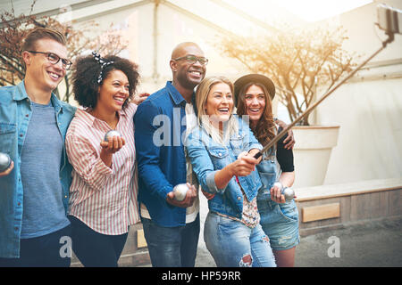 Gruppe von jungen, schönen Menschen, Männer und Frauen in Freizeitkleidung, stehen innen drinnen Petanque Spielplatz Selfie mit Selfie stick Stockfoto