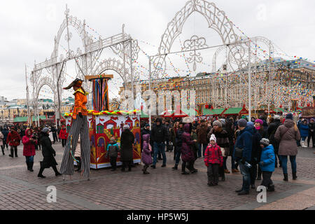 Moskau, Russland. Sonntag, 19. Februar 2017. Gesamtansicht der überfüllt und Manege Quadrat des Festivals dekoriert. Nicht identifizierte Stelzenläufer Walker unterhält das Publikum. Maslenitsa, Pfannkuchen, Käse-Tarif-Week-Festival, Karneval begann in der Stadt. Menschen genießen Straßentheater und heißen Pfannkuchen essen. Dies ist auch Abschied vom Winter-Festival. Der Tag ist Warm (+2C, über 36F) aber düster. © Alex Bilder/Alamy Live-Nachrichten Stockfoto