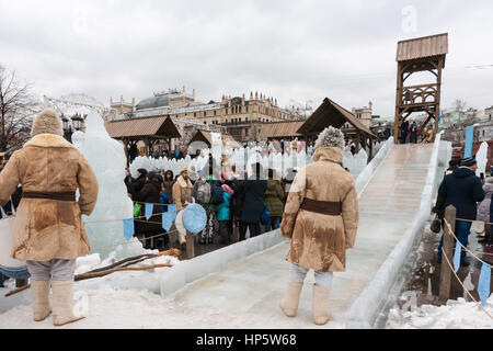 Moskau, Russland. Sonntag, 19. Februar 2017. Eis-Folie oder Eis-Lauf für Kinder durch den Schnee Festung auf Revolution Quadrat - der Hauptbereich des Festivals. Servicepersonal kümmert sich um und hilft Kindern sicher gleiten. Maslenitsa, Pfannkuchen, Käse-Tarif-Week-Festival, Karneval begann in der Stadt. Menschen genießen Straßentheater und heißen Pfannkuchen essen. Dies ist auch Abschied vom Winter-Festival. Der Tag ist Warm (+2C, über 36F) aber düster. © Alex Bilder/Alamy Live-Nachrichten Stockfoto
