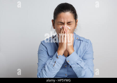 Brünette in einem Gewebe Niesen Stockfoto